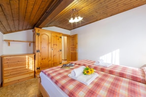 A bedroom with wooden furniture, a bed with a plaid bedspread, and a wooden wardrobe. - Eden Ski in - Ski out 50m, Livigno, Italy (Livigno)
