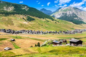 A village with traditional houses, a river, and mountains in the background. - Eden Ski in - Ski out 50m, Livigno, Italy (Livigno)