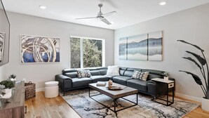 A modern living room with a sectional sofa, a coffee table, and artwork on the walls.