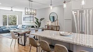 A modern kitchen with a granite island, stainless steel appliances, and pendant lighting.