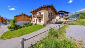 Un chalet de montagne avec une façade en bois, une allée pavée et une vue sur le paysage environnant.