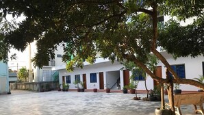 A courtyard with a tiled floor, potted plants, and a wooden bench. - MN Apartment (Siem Reap)