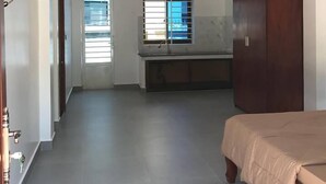 A bedroom with a bed, a wardrobe, a ceiling fan, and a window with bars. - MN Apartment (Siem Reap)