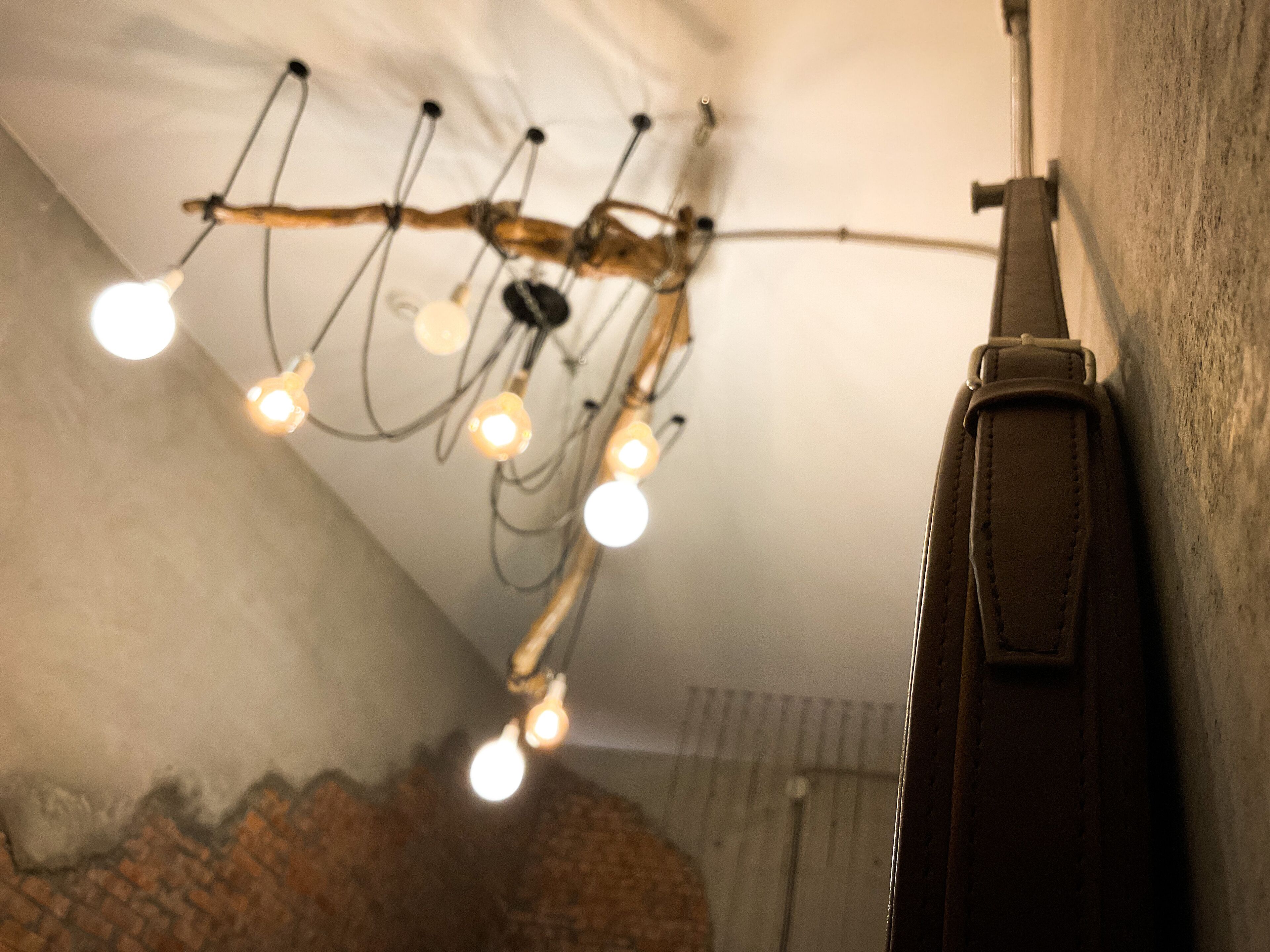 A ceiling with exposed wiring and light bulbs, a brick wall, and a leather strap.