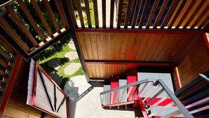 A spiral staircase with wooden railings and red steps leading to an outdoor area. - Little Ryukyu Hermit Crab Homestay (Liuqiu)
