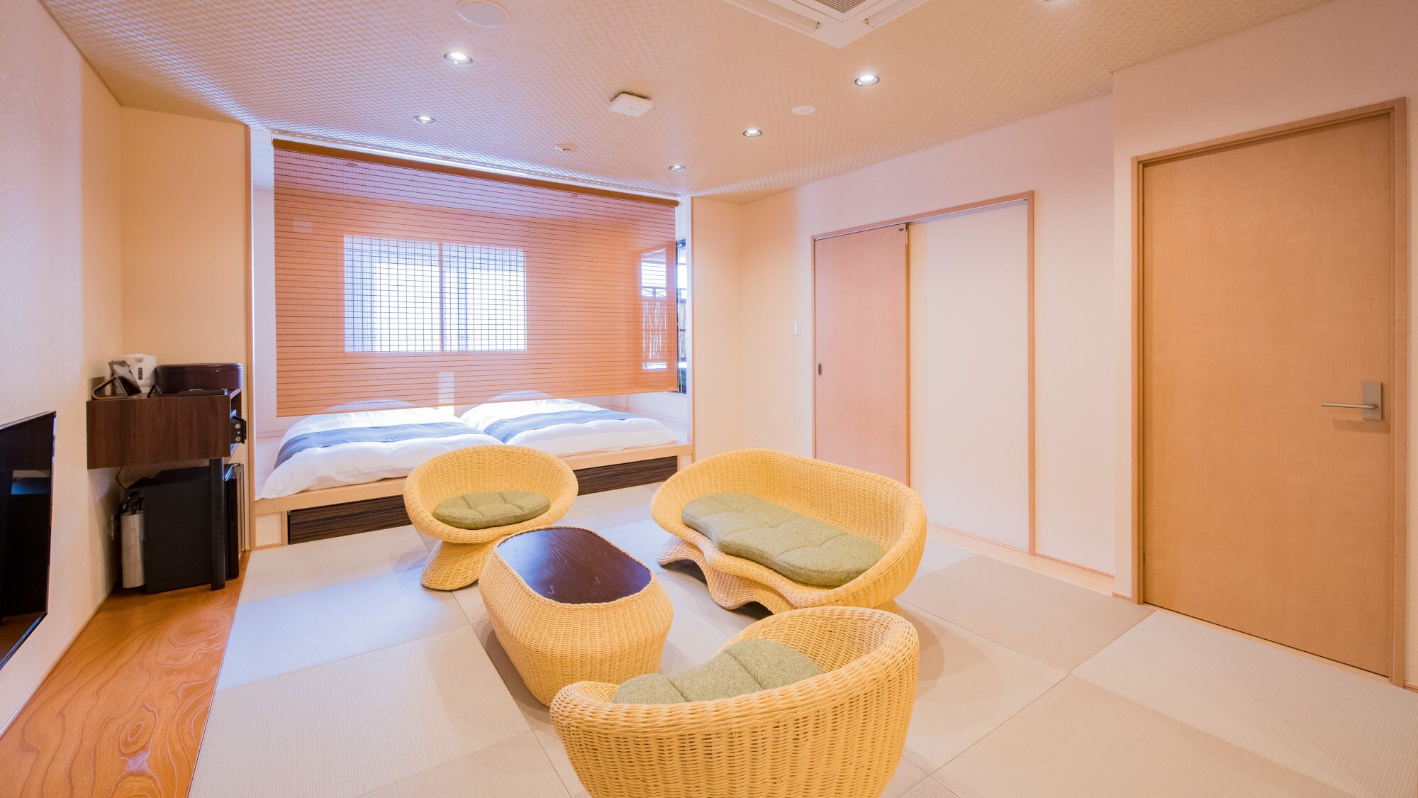 A hotel room with a bed, two wicker chairs, a small table, and a wardrobe.