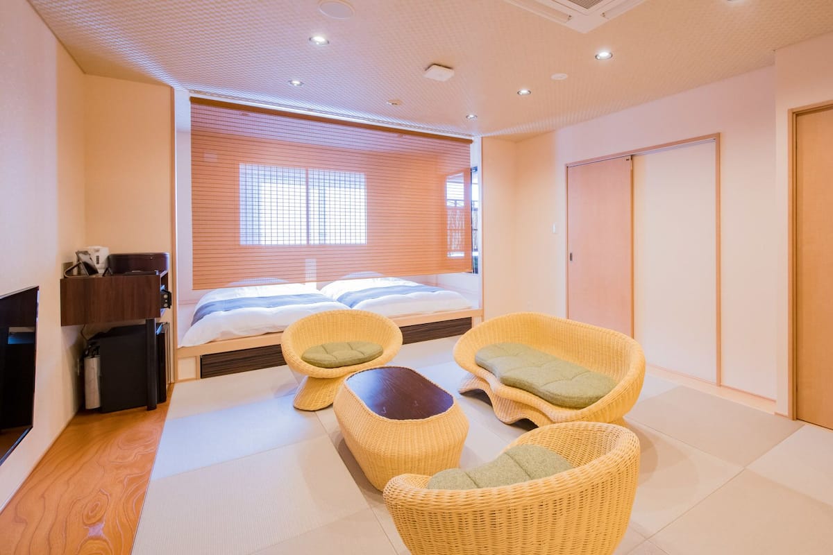 A hotel room with a bed, two wicker chairs, a small table, and a wardrobe.