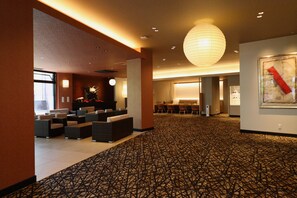 Un hall d’hôtel comprenant des espaces aménagés avec des sièges, un comptoir de réception et une grande œuvre d’art accrochée au mur.
