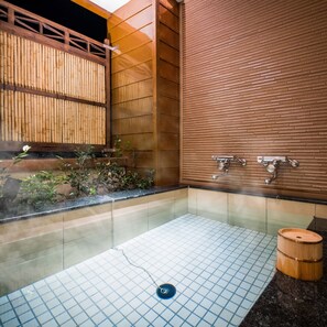 Une salle de bain de style japonais traditionnel, avec un paravent en bois de type shoji, un lavabo en pierre et un seau en bois.