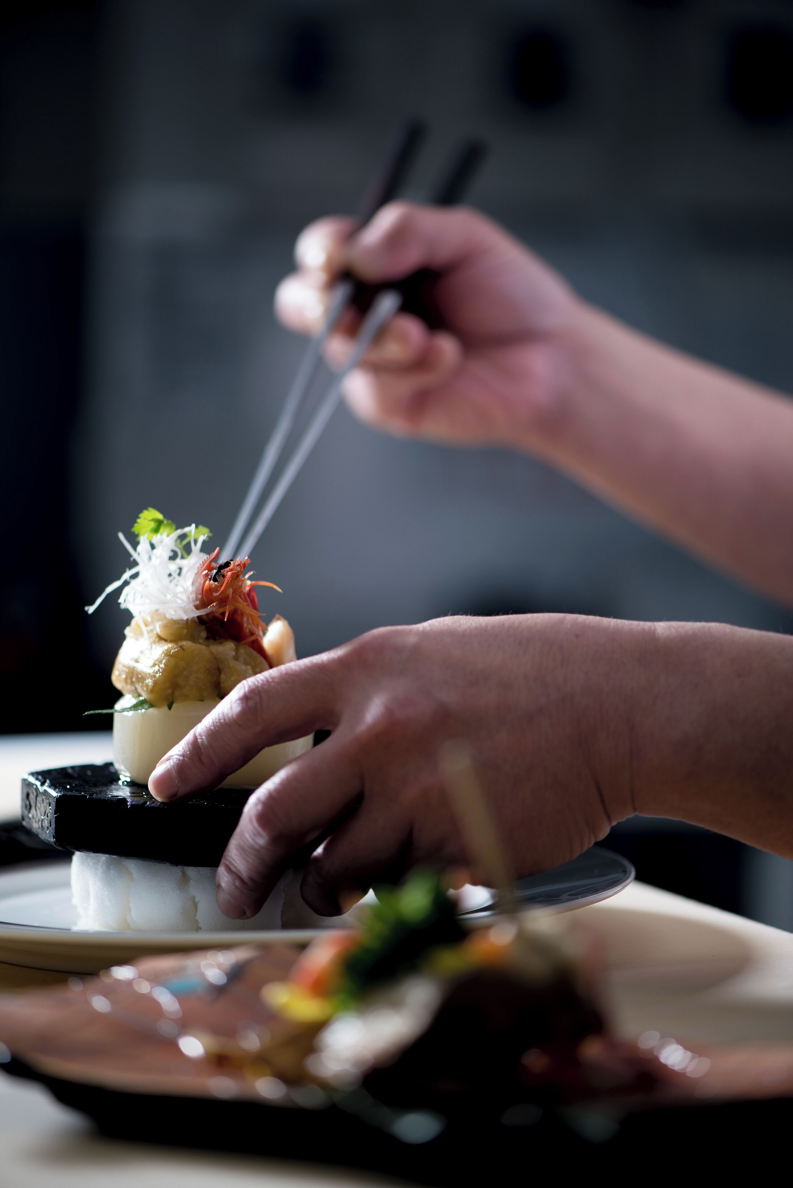 A person using chopsticks to pick up food from a plate.