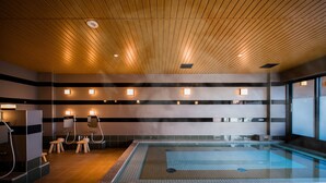 Ein moderner, überdachter Schwimmbereich mit Holzbalkendecke, mehreren Duschen und Fliesenboden.