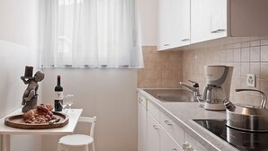 A modern kitchen with white cabinets, a window with sheer curtains, a coffee maker, and a kettle on the counter. - Double Room by Interhome (Ascona)