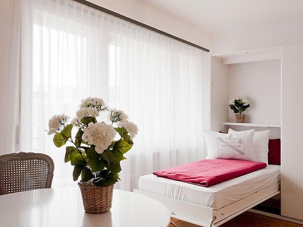 Une chambre d’hôtel avec un lit, une table à manger et une plante.
