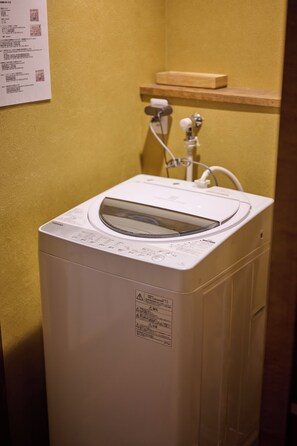 A front-loading washing machine in a room with a yellow wall.