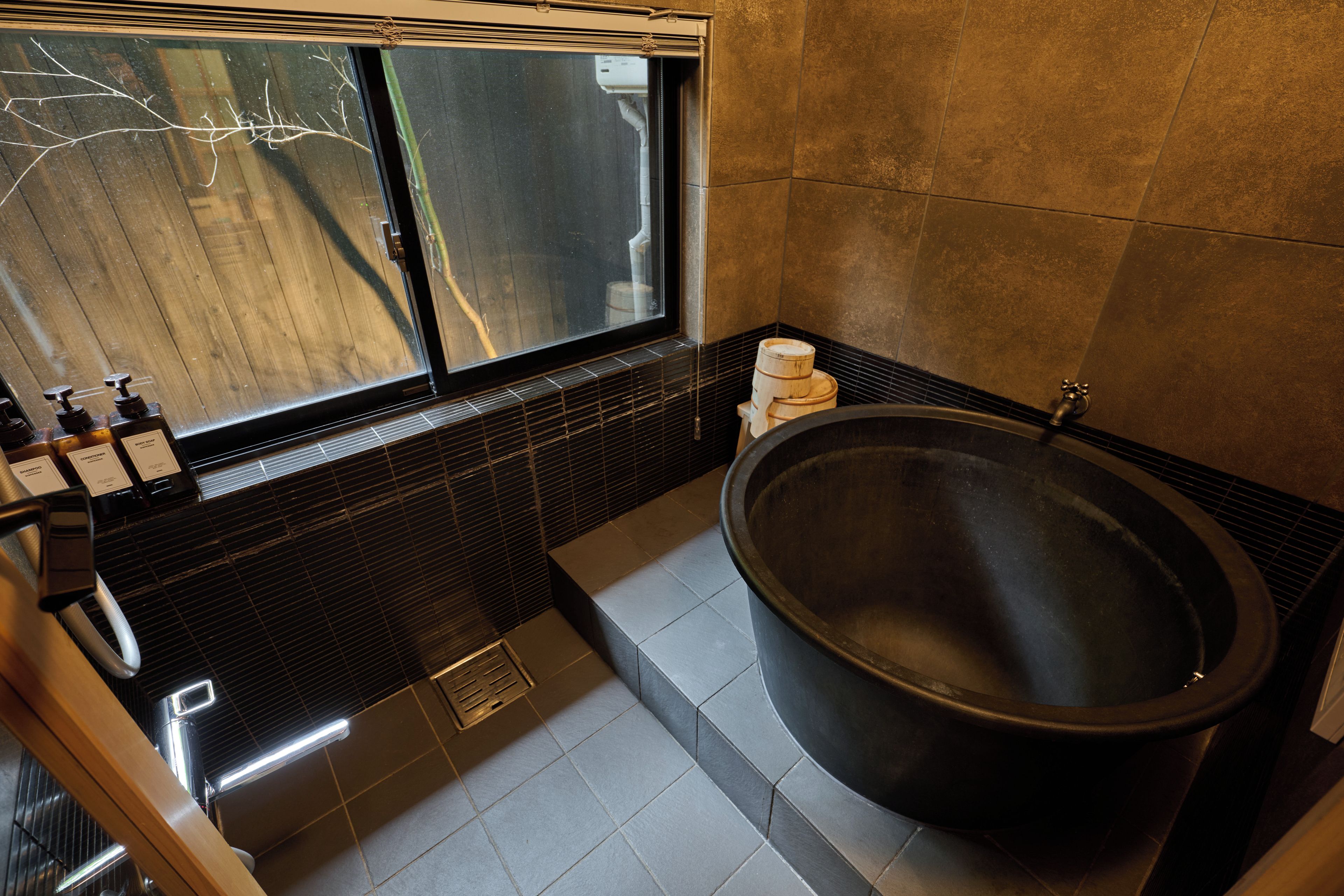 Un baño moderno con una bañera grande, una ventana y un banco de madera.