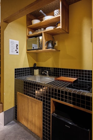 A kitchen with a black tiled backsplash, wooden cabinets, a stainless steel sink, and a black dishwasher.