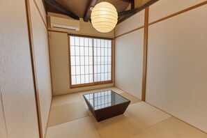 A traditional Japanese room with tatami flooring, a sliding shoji screen window, and a small table.