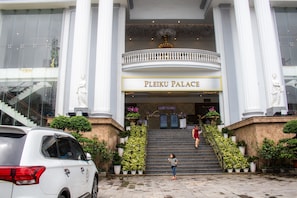 La entrada al Palacio de Pleiku con una imponente escalera, grandes columnas y plantas en macetas.