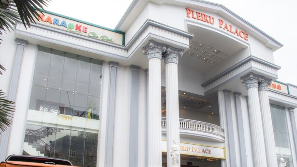 Rakennuksessa on kyltti, jossa lukee ”PLEIKU PALACE”, ja toinen kyltti, jossa lukee ”KARAOKE GIA DUK”.