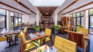 A modern restaurant with wooden furniture, a central bar, and large windows. - Araya Angkor Residence (Siem Reap)