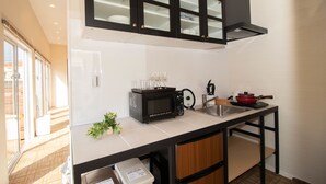 Cocina compacta con microondas, lavamanos y armarios.