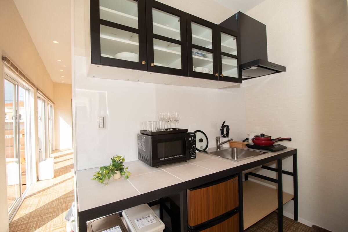 Cocina compacta con microondas, lavamanos y armarios.