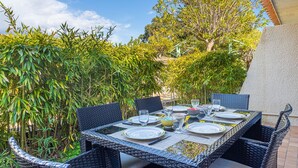 An outdoor dining area with wicker furniture and a table set for four. - Cap Nègre : Domaine de la Pinède by Interhome (Le Lavandou)