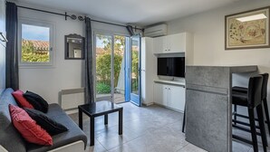 A modern apartment with a sofa, a small table, a kitchen area, and a dining area. - Cap Nègre : Domaine de la Pinède by Interhome (Le Lavandou)