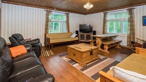 Un salon chaleureux avec un plafond en bois, un canapé, un divan en cuir, une table en bois et un téléviseur.