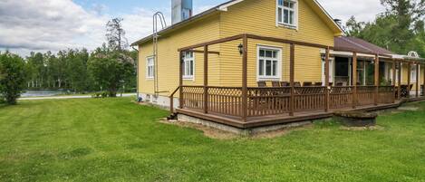 A yellow house with a wooden deck and a chimney.