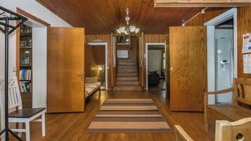 Un interior de madera con una escalera que lleva a un segundo piso, un sofá y un radiador.