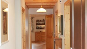 Ein Flur mit Holzdielen und Türen, der zu einem Raum mit Holzschrank und Spiegel führt.