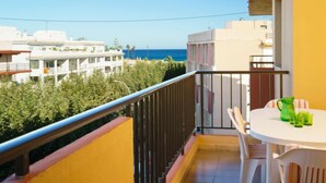 A balcony with a white table and chairs, a green pitcher, and a view of the sea and neighboring buildings. - Galicia Javea by Interhome (Jávea)