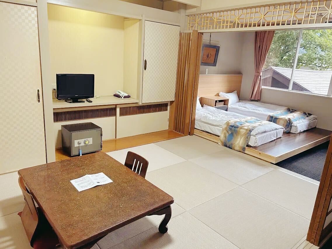 Een hotelkamer met een bed, een bureau met een computer, een stoel en een tafel.
