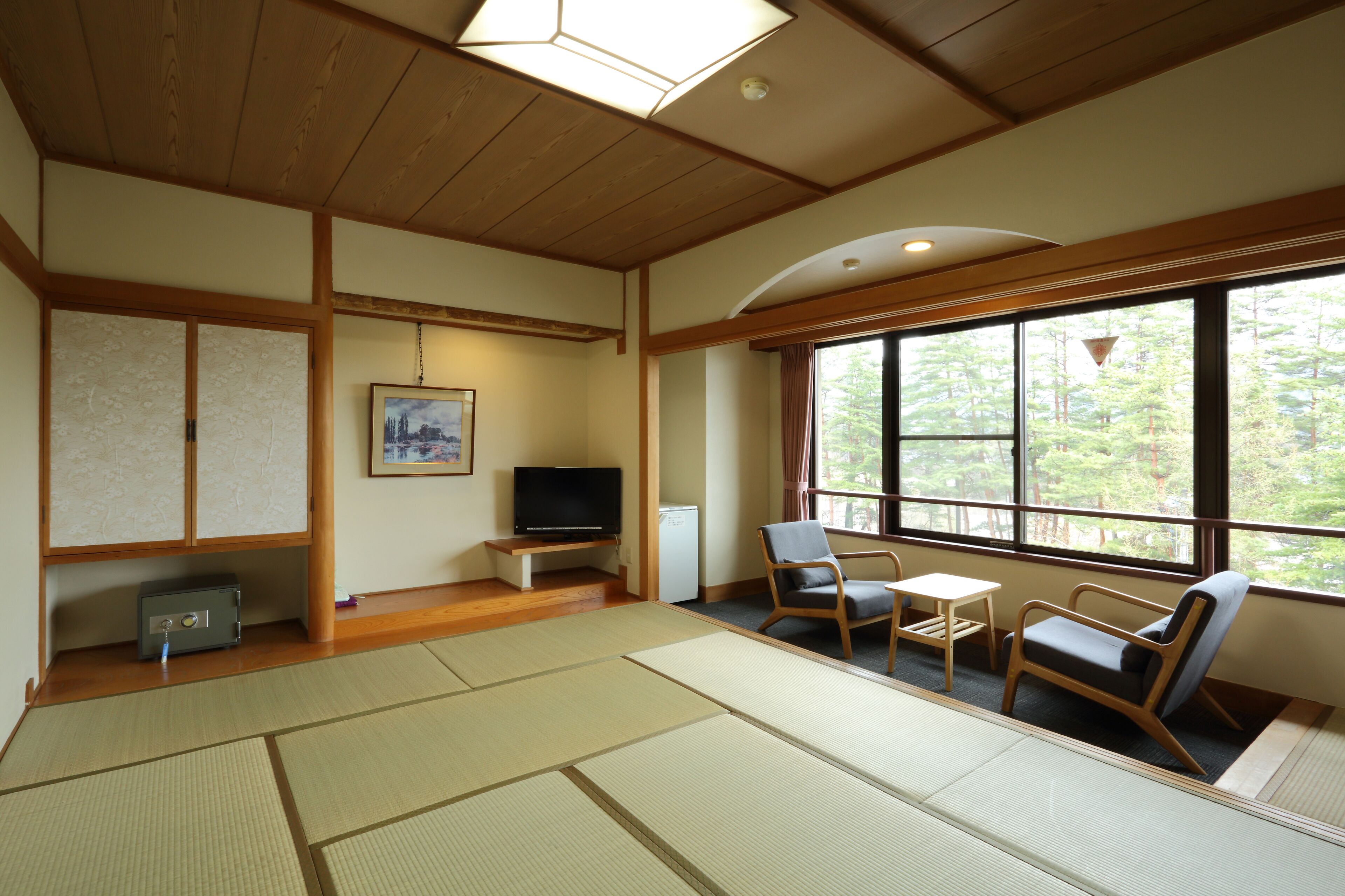 A traditional Japanese-style room with tatami flooring, a television, a small table, and a chair.