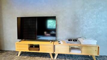 A wooden TV stand with a flat-screen TV, a remote control, and a pair of slippers.