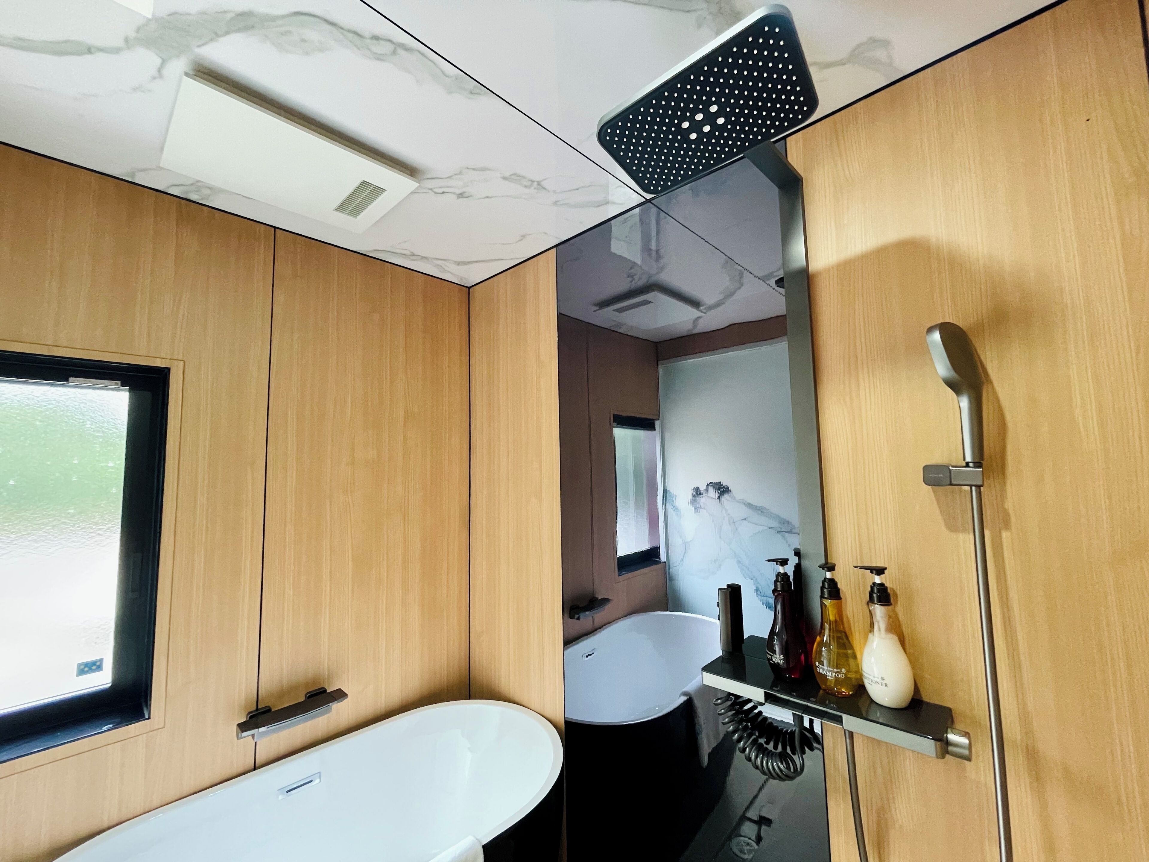 A modern bathroom with a freestanding bathtub, a showerhead, and a mirror with a decorative wall.