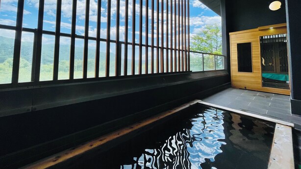 A modern interior with a large window, a wooden door, and a reflective pool. - Kurobe Sun Valley Hotel (Omachi)