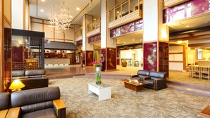 A spacious lobby with leather seating, a coffee table, and a vase with flowers. - Kurobe Sun Valley Hotel (Omachi)