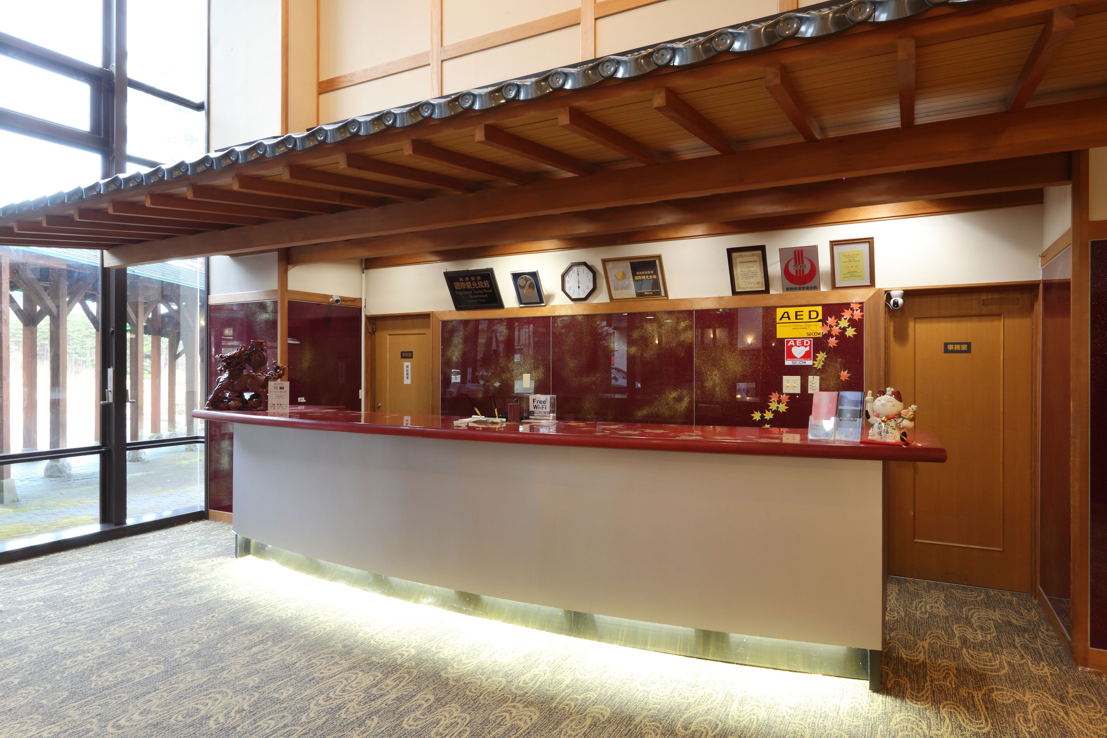 A reception desk with a wooden ceiling, framed certificates, and an AED sign.