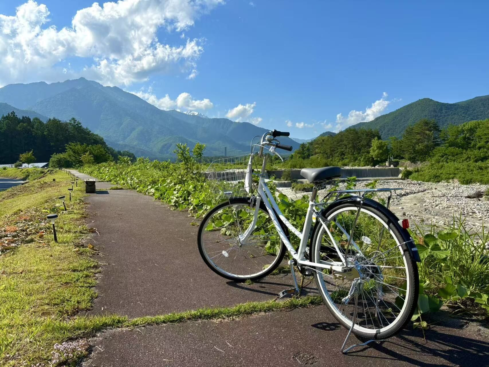 A bicycle parked on a paved path with a scenic mountain backdrop.