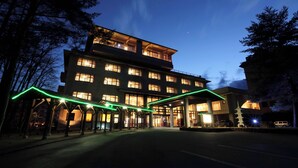 A multi-story hotel with a covered entrance and a pagoda-like structure in front. - Kurobe Sun Valley Hotel (Omachi)