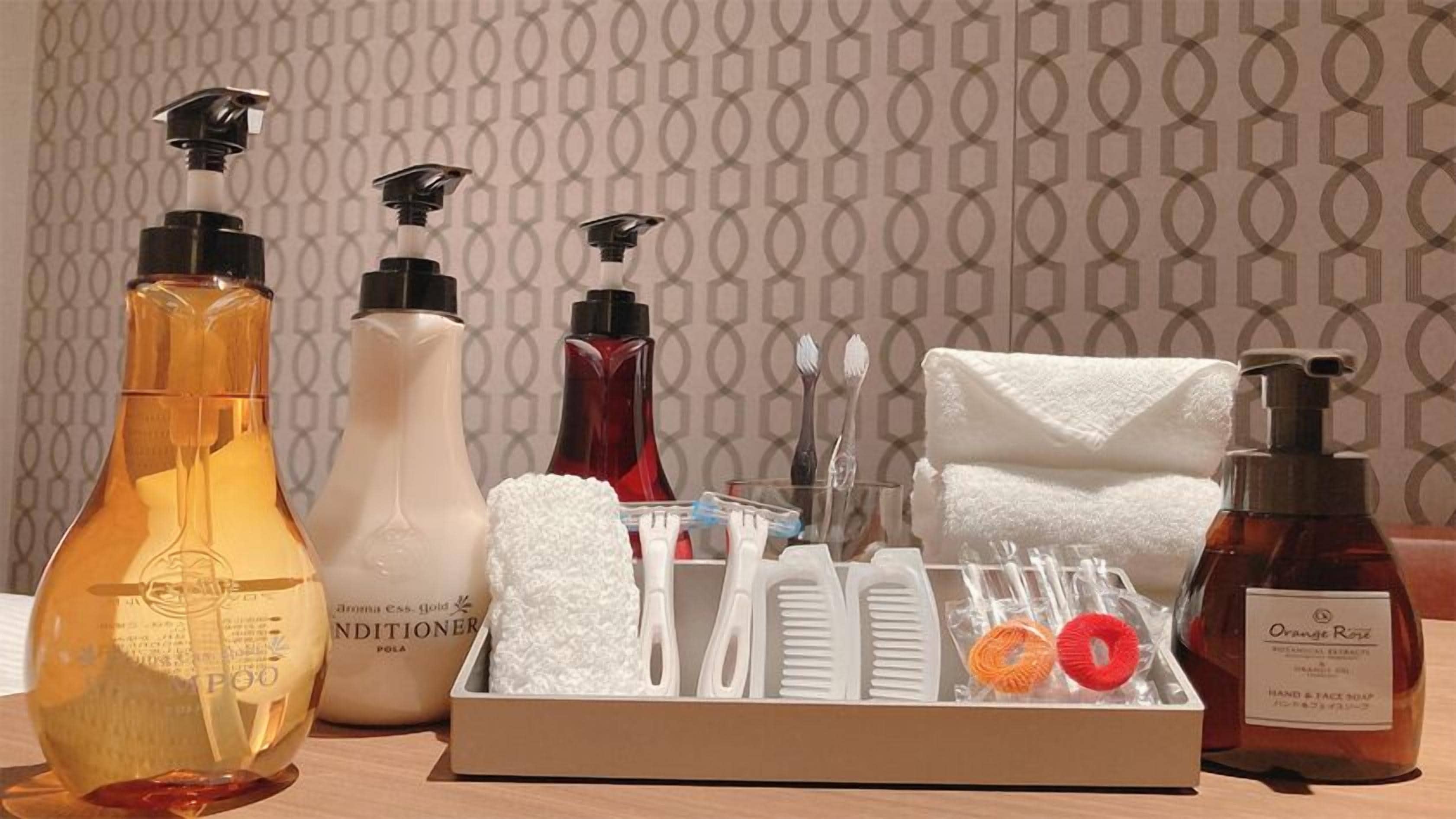 En badeværelsesvask med toiletartikler, herunder shampoo, balsam, håndsæbe og et håndklæde.