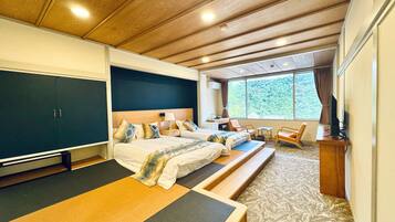 A spacious bedroom with a large bed, a desk, and a window with a view of trees.