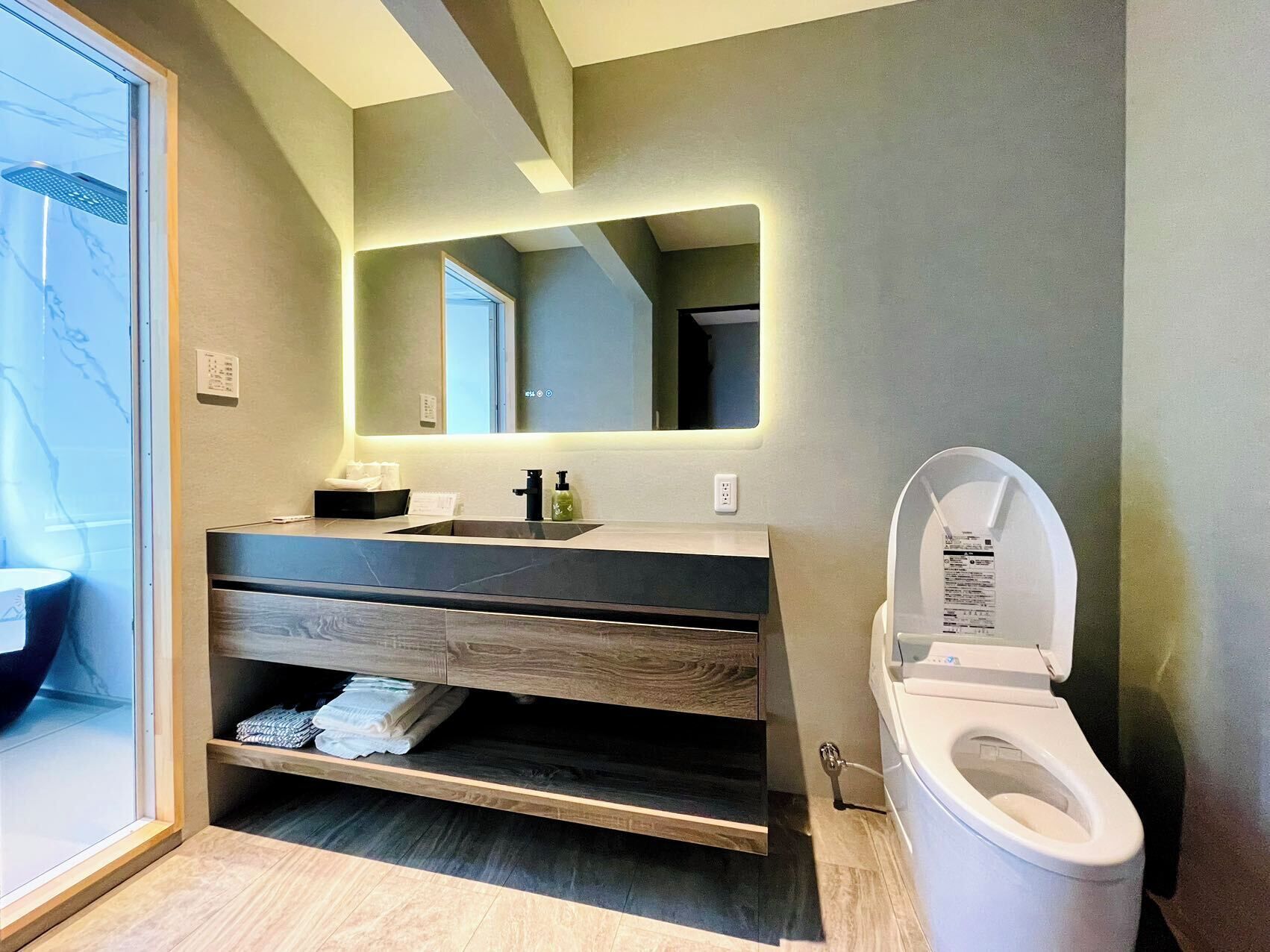 A modern bathroom with a wooden vanity, a large mirror, and a toilet.