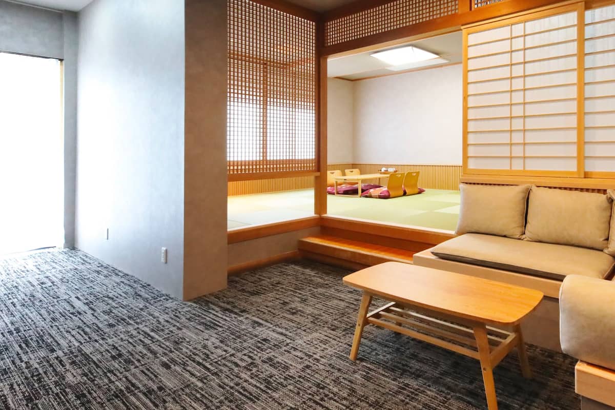 A traditional Japanese room with tatami flooring, a low wooden table, a sofa, and a shoji screen.