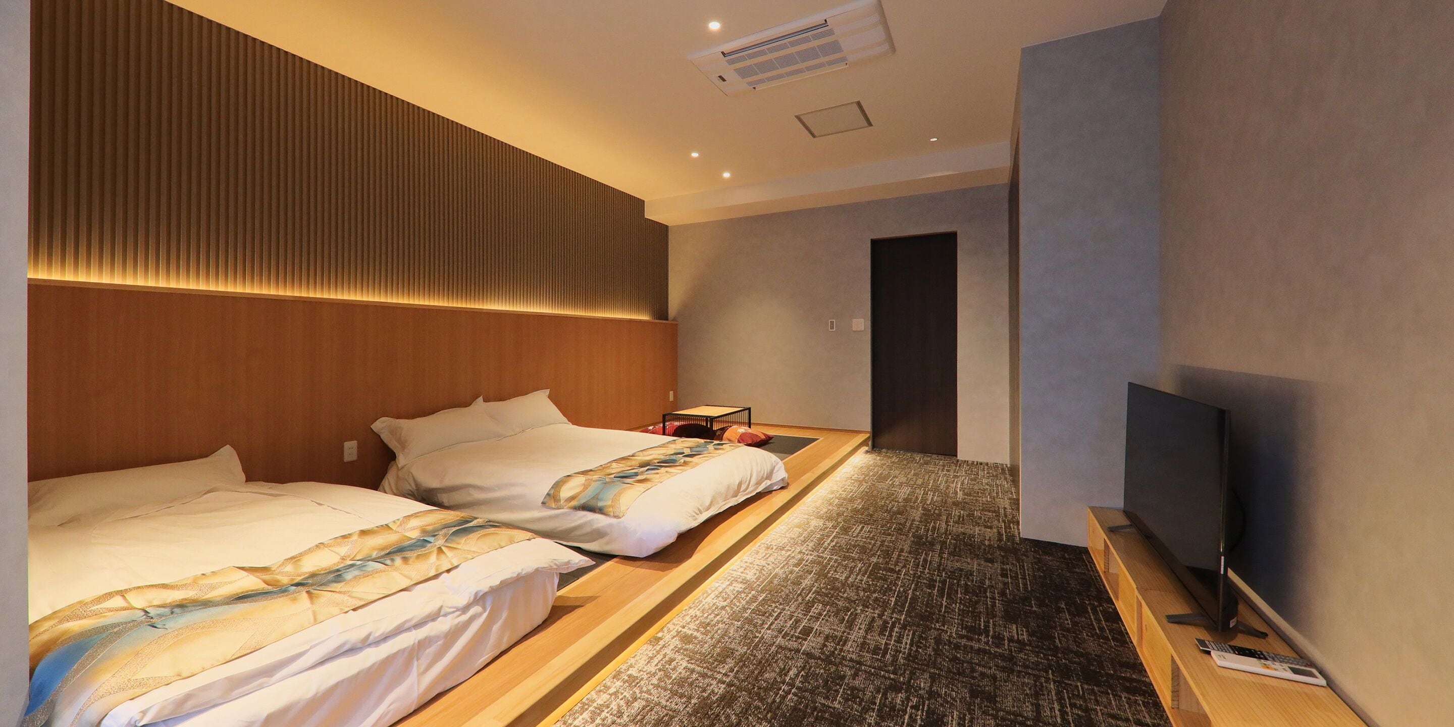 A hotel room with two beds, a TV, and a small desk.