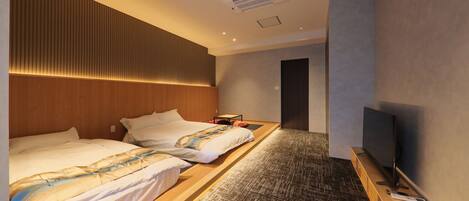 A hotel room with two beds, a TV, and a small desk.