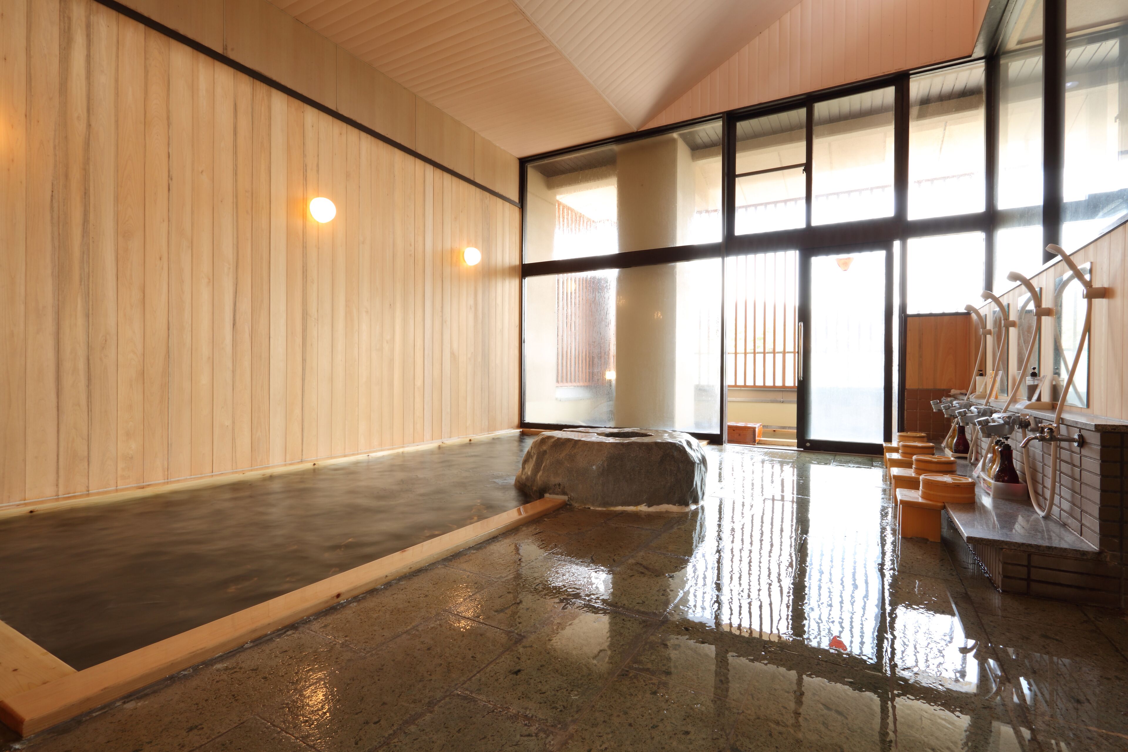 Una amplia piscina interior con una pared de madera y una partición de vidrio.