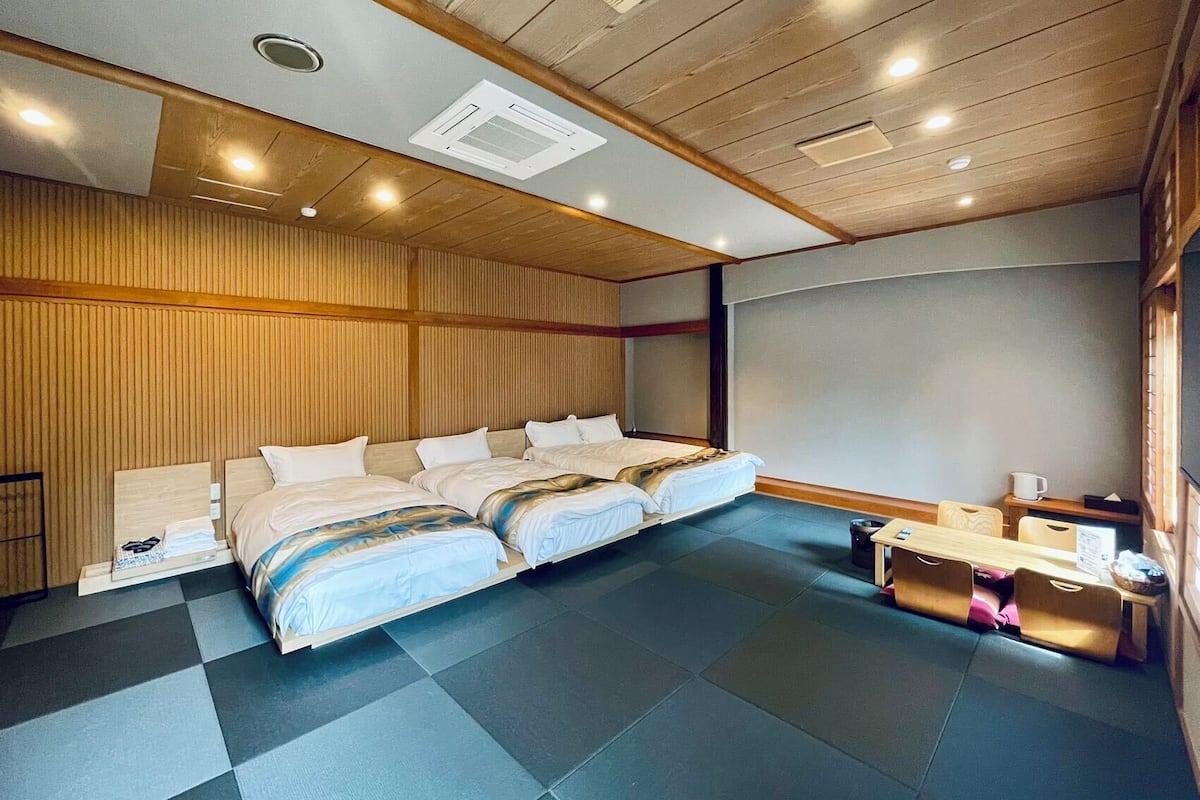 A modern hotel room with a large bed, a wooden ceiling, and a small desk with a chair.